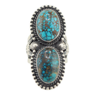 The “Twin Spirits” Revival Ring by Derrick Gordon (Navajo) features two large oval turquoise stones with brown matrix, each set in a decorative, beaded-edge silver setting.