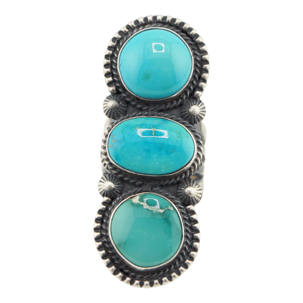 The “Twin Spirits” Revival Ring by Derrick Gordon (Navajo) showcases three vertically set oval turquoise stones in detailed silver bezels with rope-style edges and delicate silver accents between the stones.