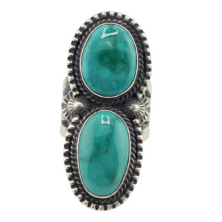 The “Twin Spirits” Revival Ring by Derrick Gordon (Navajo) features two vertically set oval turquoise stones, each framed by detailed rope and bead borders with intricate silverwork between them.