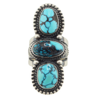 The “Twin Spirits” Revival Ring by Derrick Gordon (Navajo) is a silver ring showcasing three vertically set oval turquoise stones with black veining and intricate beaded edging around each stone.