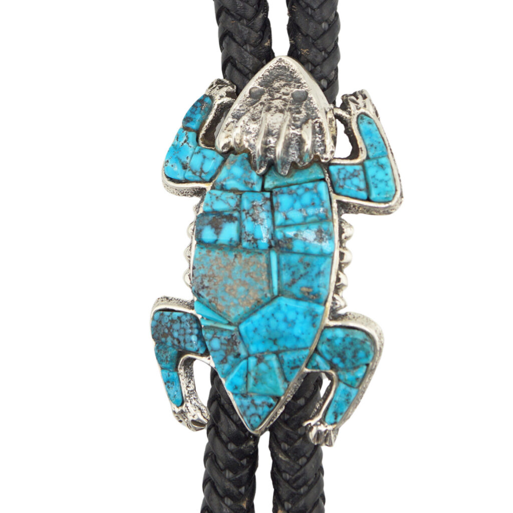The Horned Toad Bolo by Lester James (Navajo) features a silver, lizard-shaped slide inlaid with turquoise, on a braided black leather cord.