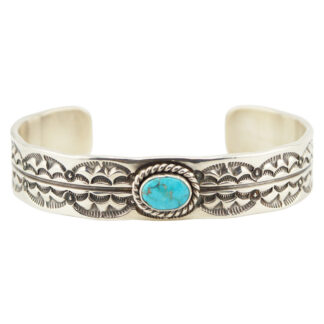 A silver cuff bracelet with intricate engraved patterns and a central oval turquoise stone set in a twisted rope design.