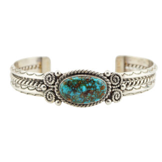 A silver cuff bracelet featuring a central oval turquoise stone with brown veining, surrounded by intricate rope and swirl detailing on the band.