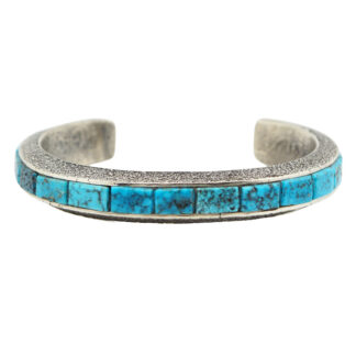 A silver cuff bracelet featuring a row of rectangular turquoise stones set along the top, with a textured finish on the metal.