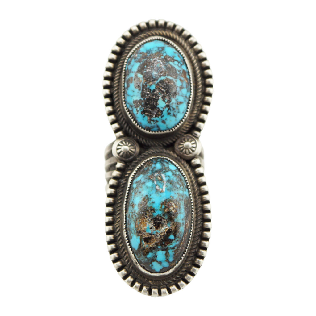 A silver ring featuring two large, oval-shaped turquoise stones with black and brown matrix patterns, set vertically in detailed, decorative bezels.