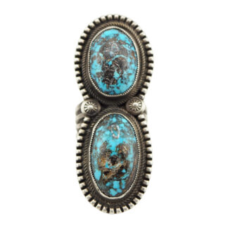 A silver ring featuring two large, oval-shaped turquoise stones with black and brown matrix patterns, set vertically in detailed, decorative bezels.