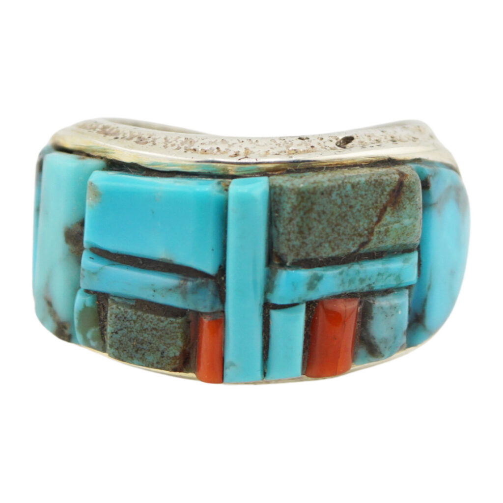 A silver ring featuring an inlay of turquoise and coral stones arranged in a geometric, mosaic-like pattern.