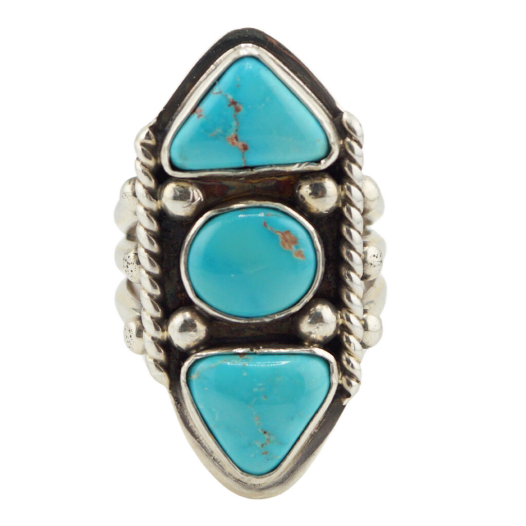 A silver ring featuring three turquoise stones—two triangular and one oval—set vertically with intricate silver detailing around each stone.