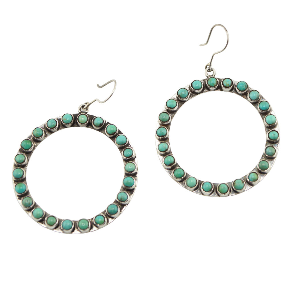 A pair of circular hoop earrings decorated with small turquoise stones set evenly around the silver hoops, each with a simple hook for fastening.
