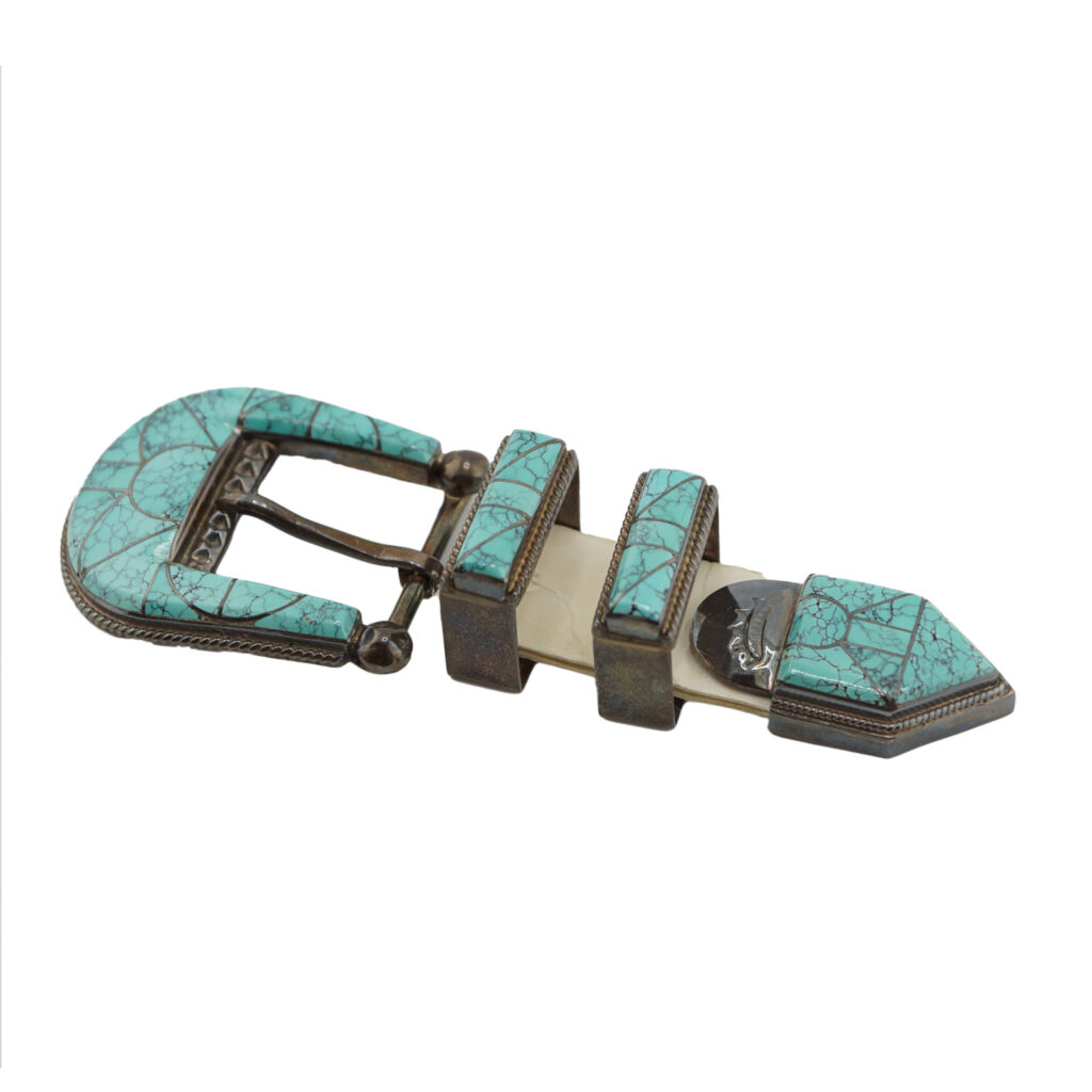 The Vintage Ranger Buckle Set by Stanford & Diane Cooche (Zuni) features a buckle, two loops, and a pointed tip, all adorned with turquoise inlays and detailed silverwork in a matching decorative pattern.